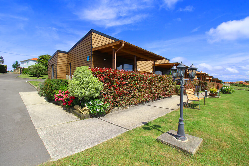 Row of wooden bungalows with lamp post and garden